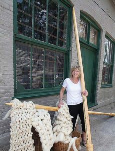 Jeanette Huisinga, owner of The Yarn Studio, stands with the world’s largest knitting needles and the stitches she muscled together at the local elementary school to qualify for the Guinness World Records. (Photo provided)