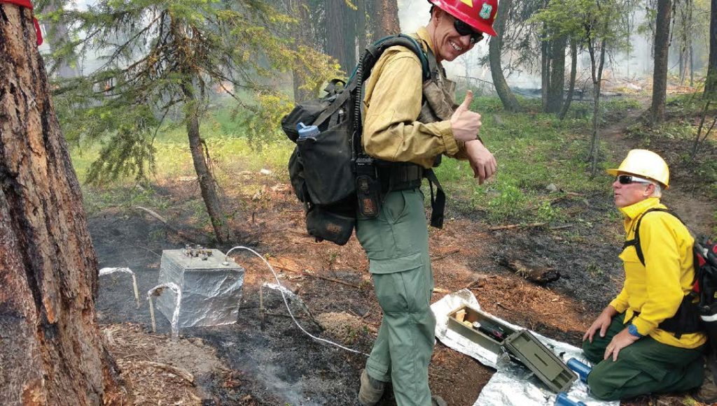 Wesley Page, forestry technician, and Steve Baker, chemist, conduct research on smoldering fires. They are measuring the temperature at specific depths and consumption while collecting emissions samples of smoldering duff after a prescribed fire has burned through a small experimental plot in central Washington. The silver box is a portable chamber that fills with smoke for one minute and allows them to calculate the rate of carbon emission per unit area and to characterize the gases collected in the blue bottle. It is part of a Strategic Environmental Research and Development Program-funded study of smoldering combustion. (Photo by Matt Ellis)