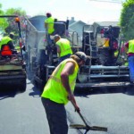 Public works employees in Des Moines, Iowa, pave asphalt.