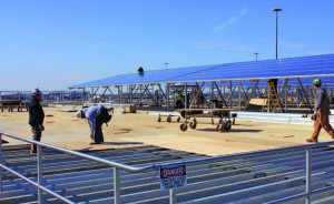 Workers continue to place photovoltaic modules over one of the tanks at the Camden wastewater treatment plant while others secure wood over metal supports so work can be completed safely. (Provided by groSolar)