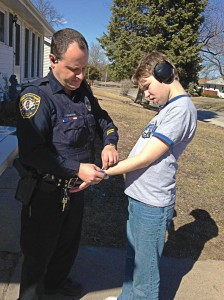 Quincy, Ill., Officer Tom Liesen fastens a tracking device to the wrist of a 19-year-old boy with autism. (Photo provided)