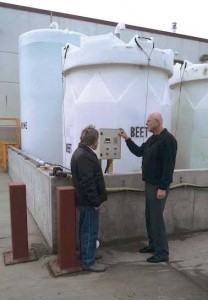 Reeder, right, speaks with an employee in front of the Council Bluffs anti-icing/deicing storage tanks. The beet tank is 6,000 gallons in size; the two brine tanks are 10,000 and 7,500 gallons; and the calcium is 6,000 gallons. (Photo provided)