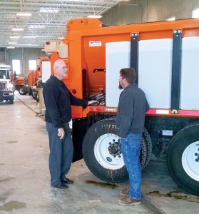 This Council Bluffs, Iowa plow truck is outfitted with solution tanks on the side. Public Works Director Greg Reeder’s hand is on the hoses that connect the tanks to the sprayer as he gives instructions to an employee. (Photo provided)