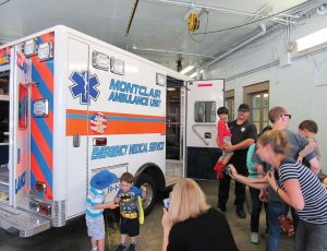 Montclair, N.J., EMT Jason Batruk — in the navy T-shirt and holding a child — is shown giving an ambulance tour to some local children during Montclair’s 2016 Walnut Street Fair. The fair is held just a couple of weeks before National EMS Week, so the ambulance service has piggybacked onto that event to do an open house and show equipment to the public. (Photo provided)