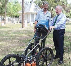 From left, Thomas Pluckhahn, associate professor and archaeologist at the University of South Florida, and Tampa Mayor Bob Buckhorn test out a ground-penetrating radar unit in Oaklawn Cemetery. (Photo provided)