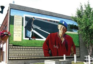 Martin Biondich, known around town simply as “Marty,” was an amiable downtown mainstay who swept the streets and greeted everyone with a smile. The baseballs embedded in the mural were purchased by residents for $50 each to help raise funds for subsequent murals. (Photo provided)