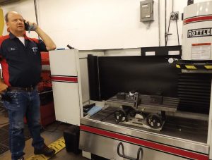 Tom Rohr, owner-operator of Advance Engine in Plymouth, Ind., takes a call while standing next to the Rottler Manufacturing CNC resurfacing machine his shop got last year. (Photo by Denise Fedorow)