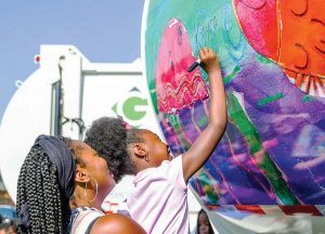 A young artist signs her painting on the back of a Greenville, N.C., sanitation truck. (Photo provided)