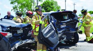 In response to the hazardous material drill’s findings, the city of Warsaw, Ind., is leasing new Kenwood radio devices for the street department, wastewater department, cemetery, parks department, airport, police department and fire department. Pictured, a firefighter with the Warsaw-Wayne Fire Department carries a door away from a vehicle as his teammates work to quickly extract a passenger involved in a motor-vehicle accident. (Photo by Maggie Kenworthy/Ink Free News)