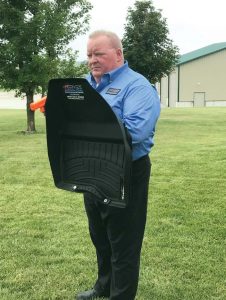 Keith Brown holds his invention, Attack Mats, which is a floor mat that doubles as a light-weight ballistic shield. Still functional as floor mat, it is easily accessible should an officer need it while responding to a call. (Photo provided)