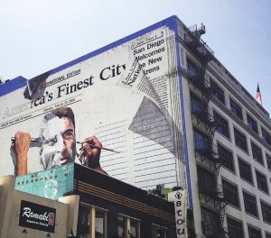 A newspaper article about how San Diego, Calif., is welcoming its immigrants goes up on the side of a building in the city. (Photo provided by Welcoming San Diego)