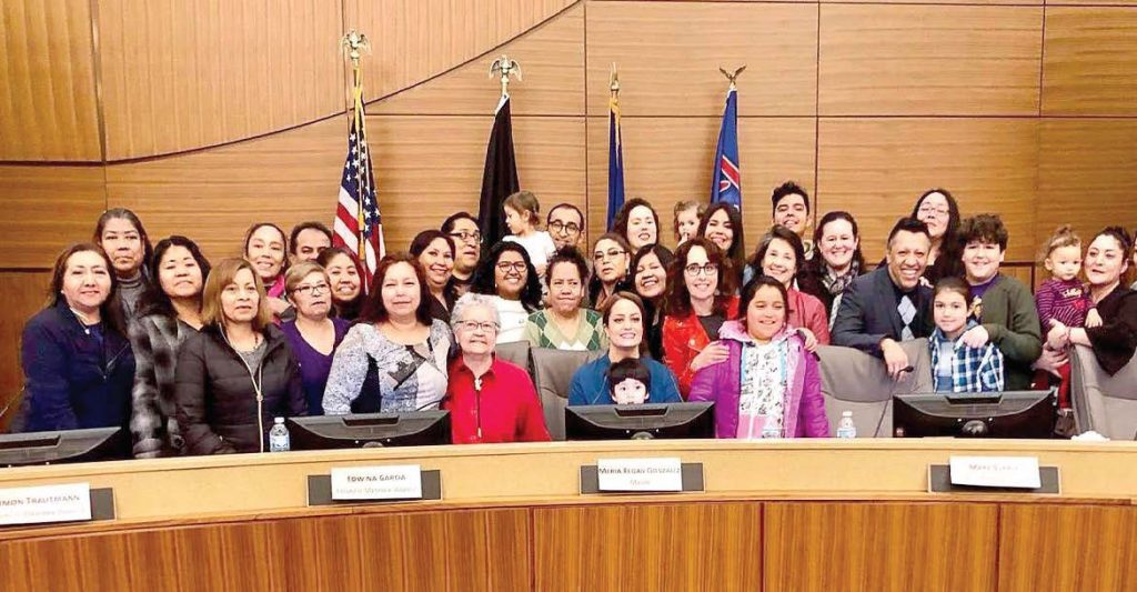 Marie Regan Gonzalez, the new mayor of Richfield, Minn., poses with members of the community as she sits in her new chair. She is the first Latina mayor in Minnesota history. (Photo provided)